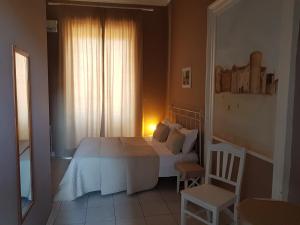 a bedroom with a bed and a chair and a window at Hotel Biscari in Catania