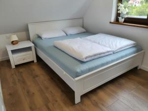 a bed with two pillows on it with a night stand at Stepnicka Keja in Stepnica
