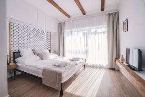 a white bedroom with a large bed and a television at Mathias Rex in Szentendre