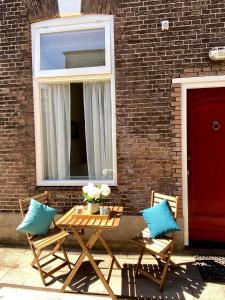 Basic Little House Scheveningen في شيفيننغن: طاولة خشبية مع كرسيين ونافذة