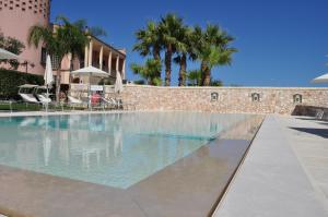 - une piscine en face d'un bâtiment avec des palmiers dans l'établissement Villa Rosa Antico Dimora Storica, à Otrante