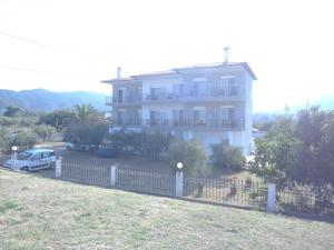 uma grande casa branca com uma cerca em frente em Vergina Pension em Sarti