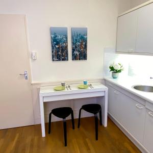 a kitchen with a white table and two stools at Basic Little House Scheveningen in Scheveningen