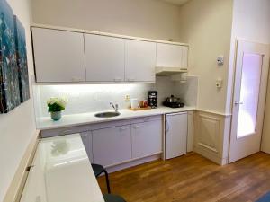 eine Küche mit weißen Schränken und einem Waschbecken in der Unterkunft Basic Little House Scheveningen in Scheveningen