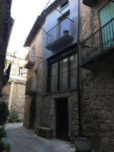 - un vieux bâtiment en pierre avec un balcon et une porte dans l'établissement Casa Tato Figuerola d'Orcau, à Figuerola de Orcau