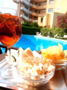 a glass of wine and a bowl of food on a table at Hotel Tritone in Porto San Giorgio +13 photos
