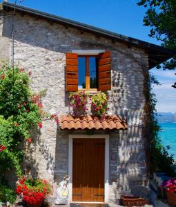 ein Steinhaus mit einem Fenster, einer Tür und Blumen in der Unterkunft Casa Fornaci in Peschiera del Garda