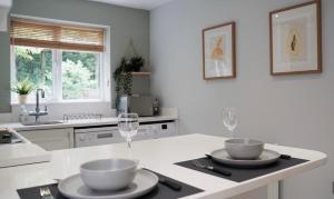 a kitchen with two bowls and wine glasses on a counter at The Pavilion - Stunning, 4 Bedroom House with Free Parking in Wakefield