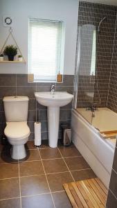 a bathroom with a toilet and a sink and a tub at The Pavilion - Stunning, 4 Bedroom House with Free Parking in Wakefield