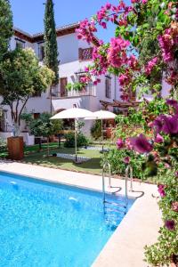 a pool in front of a building with pink flowers at Alojamiento con Encanto la Luna en el Alba in Granada