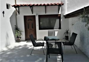 a patio with chairs and a table in front of a door at The Little Gem Under The Rocks 2 in Kastraki