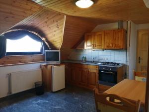 a kitchen with wooden cabinets and a window and a refrigerator at Casa Ninfea Panzió in Cserszegtomaj