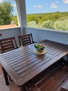 a wooden table with a bowl of fruit on a porch at Villa Arancia in Peruški