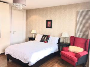 a bedroom with a bed and a red chair at CK Serviced Apartments Belfast in Belfast