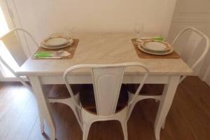 una mesa y sillas blancas con platos y vasos. en Vie d'acqua Al Morelo - City Center-BO en Bolonia