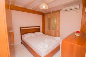 a bedroom with a white bed and a wooden dresser at Orfeas Studios in Vasiliki