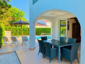 a patio with a table and chairs and an umbrella at Villa CAROLINA in Cala en Forcat