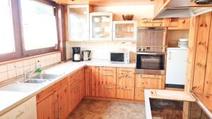 a kitchen with wooden cabinets and white appliances at Ferienhaus Waldblick in Sonnenbühl