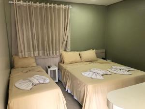 two beds sitting next to each other in a room at Hotel Roni in Itabuna