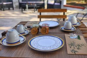 a wooden table with plates and cups and utensils at Villa Corocael in Castellabate