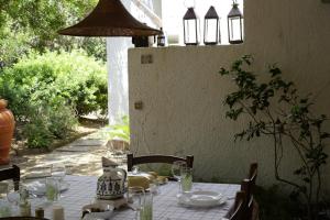 a table with a white table cloth with a cat on it at Maison Nóus in Santa Margherita di Pula