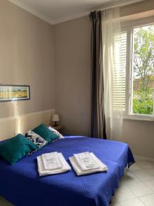 a bedroom with a blue bed with towels on it at Hotel La Perla in Marina di Massa