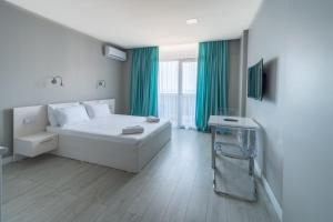 Orbi Residence Hotel Official في باتومي: غرفة نوم بسرير ابيض وستائر خضراء
