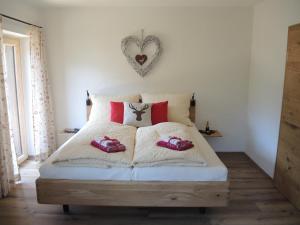 Schlafzimmer mit einem weißen Bett und roten Kissen in der Unterkunft Familienbauernhof Bairau Reifhorn in Lofer