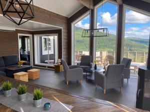 a living room with couches and chairs and windows at Pudderhytta in Sogndal