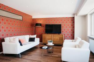 a living room with two white couches and a tv at LE 19 KLEBER climatisé in Colmar