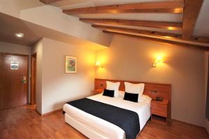 a bedroom with a large white bed with pillows at Hotel & SPA Niunit in Ordino