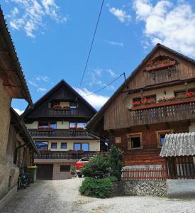 - deux bâtiments en bois avec des fleurs sur les balcons dans l'établissement Apartmaji Pavc, à Bohinj