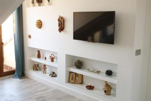 a living room with a television on a wall with shelves at Alojamiento Museo Carmelitano Alba de Tormes in Alba de Tormes