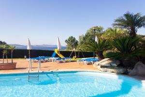 a swimming pool with tables and chairs in a resort at Hotel Canelas in Portonovo