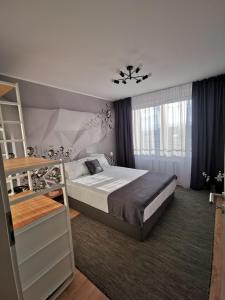 a bedroom with a bed and a large window at Cliché Luxury Apartment in Braşov