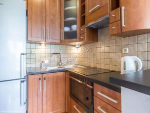 une cuisine avec des placards en bois et des comptoirs noirs dans l'établissement Willa Ewka, à Kościelisko