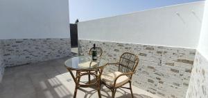 une table en verre et deux chaises devant un mur de briques dans l'établissement Apartamento Las Brisas, à Playa Blanca
