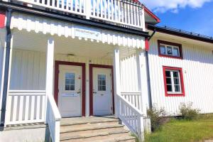 ein weißes Haus mit einer roten Tür und einer Treppe in der Unterkunft Bograngen Lgh C in Brograngen