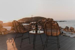 duas cadeiras e uma mesa com dois copos de vinho em Portara Seaside Luxury Suites em Naxos Chora