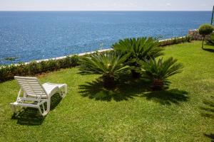 a white chair sitting on the grass near the ocean at Sky Fort Apartments in Dobra Voda