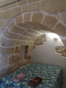 een kamer met een bed in een stenen muur bij Trullo Maria in Carovigno