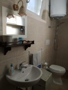 een badkamer met een wastafel, een toilet en een spiegel bij Trullo Maria in Carovigno