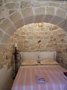 een slaapkamer met een bed in een stenen muur bij Trullo Maria in Carovigno