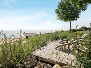 a wooden deck with benches and a boat on the water at 8 person holiday home in Tranek r in Fæbæk