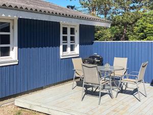 a patio with a table and chairs and a blue building at 6 person holiday home in R dby in Kramnitse