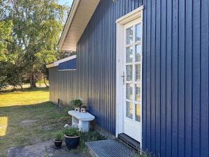a blue house with a bench next to a window at 6 person holiday home in R dby in Kramnitse
