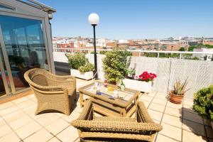 um pátio com cadeiras de vime e uma mesa na varanda em Hotel Sancho em Madri