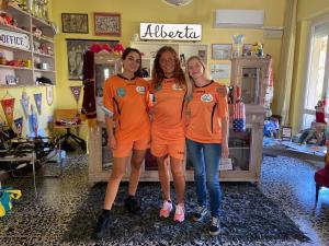 three girls in orange shirts standing in front of a mirror at Hotel il 9 in Lido di Camaiore