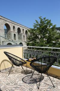 two chairs and a table on a balcony with a building at Under the Aqueduct boutique house in Kavála