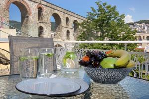 a table with a bowl of fruit and glasses of water at Under the Aqueduct boutique house in Kavála